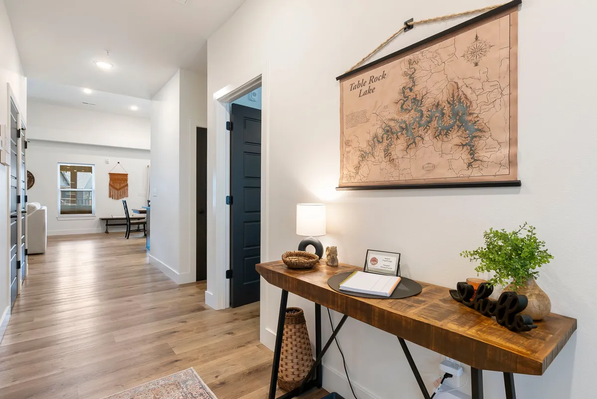 An inviting console table topped with a lamp and plant sits below a large map of Table Rock Lake, visually reinforcing the property's connection to the region's attractions. The scene suggests a point of orientation or planning for local adventures.