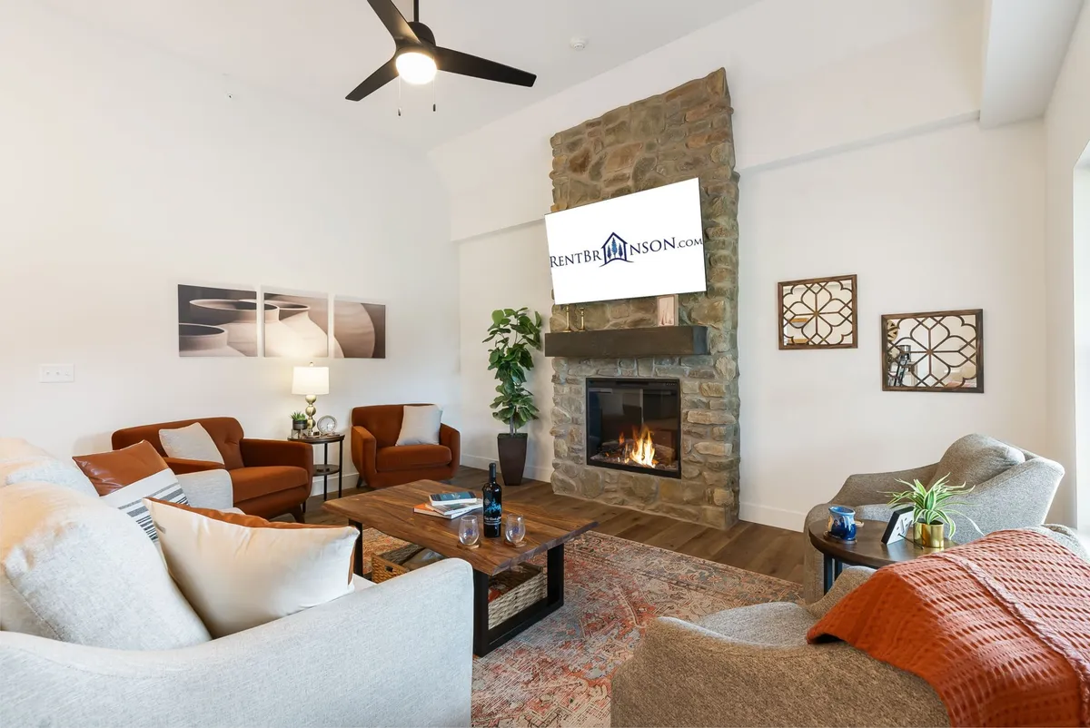 A focused view of the living area featuring a stone fireplace, plush seating, a coffee table with decor, and wall art. The ambiance is warm and inviting, perfect for group relaxation, socializing, or game nights. The fireplace serves as a central gathering point for cozy moments.
