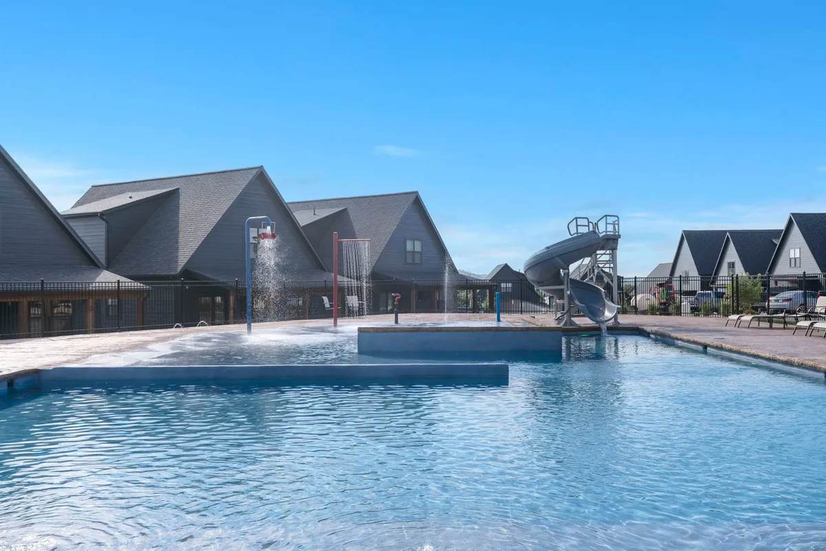 This exterior image features a vibrant swimming pool with a water slide, surrounded by lounge chairs and nearby buildings. The pool area is lively and inviting, suggesting opportunities for fun, relaxation, and community gatherings.