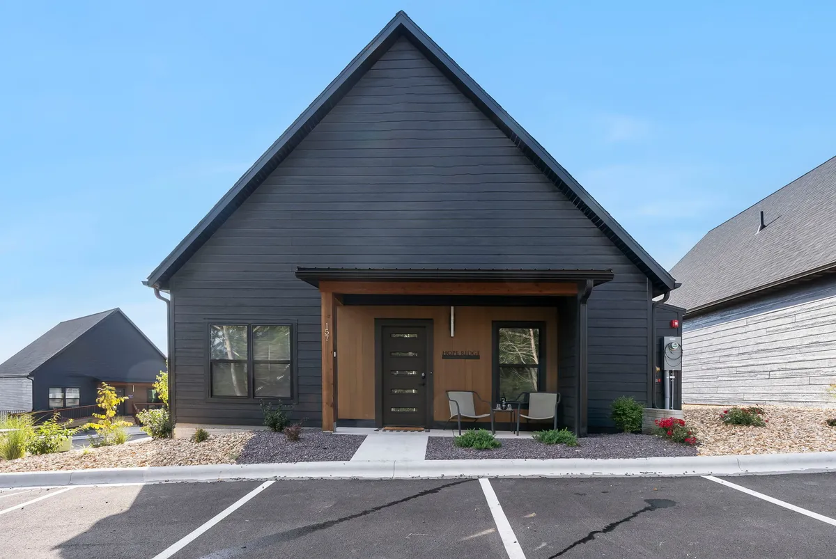 A cozy exterior scene showing a front door and adjacent outdoor seating area set among tasteful landscaping, ideal for relaxing or socializing outdoors.