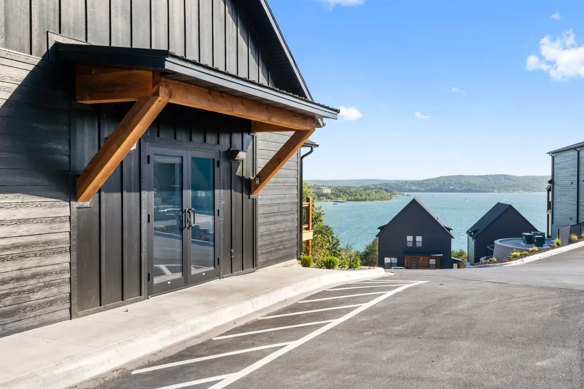 A striking exterior scene displaying the home's modern design, wooden accents, and panoramic lake view. The expansive outdoor area invites relaxation and hints at both natural beauty and local excitement within reach.
