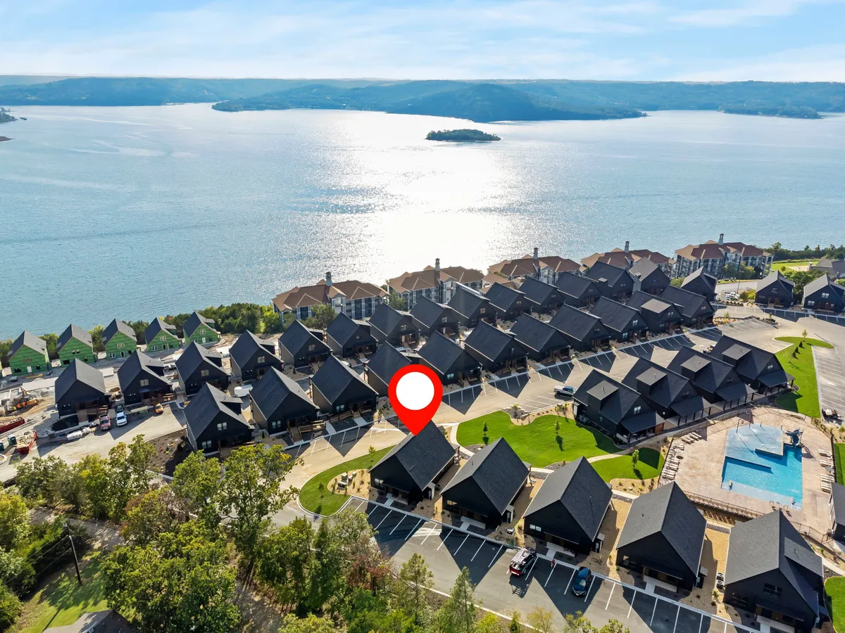A broad exterior view blending Table Rock Lake, residential homes, lush landscapes, and the pool area, illustrating the proximity of lake and recreation facilities to the community. The tranquil setting hints at endless possibilities for lakeside picnics, swimming, and outdoor adventures.