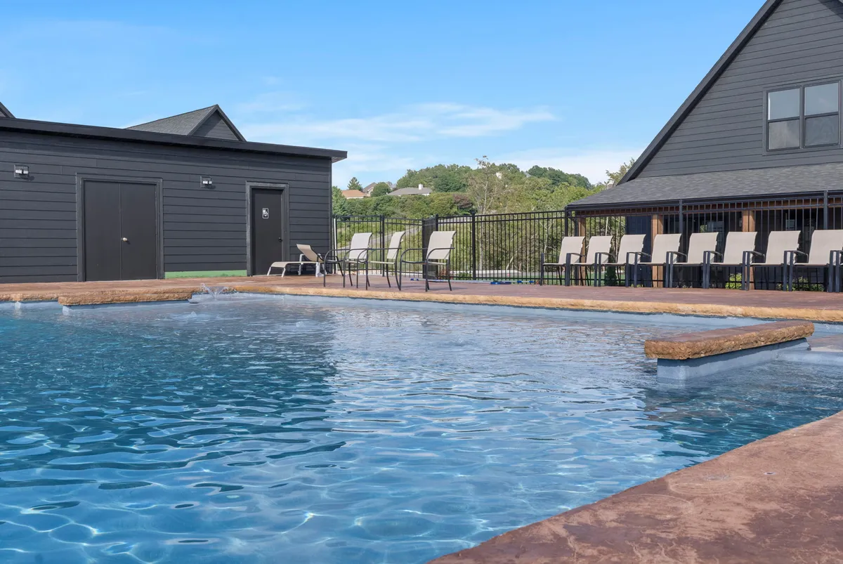 A wide view of the outdoor swimming pool, surrounded by deck chairs and a pool house, with gentle hills in the background. The tranquil setting conveys both relaxation and opportunities for recreation, with plenty of space for sunbathing or taking a swim break during the workday.